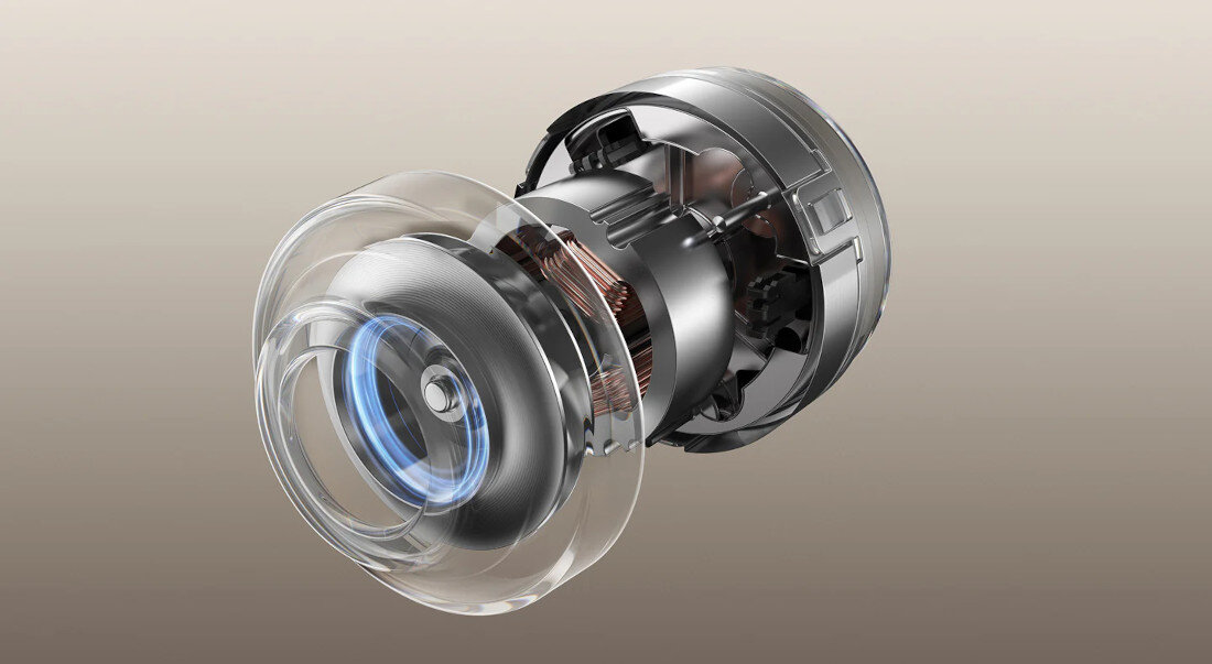 Obraz przedstawia metalowy mechanizm z przezroczystymi elementami, przypominający część silnika lub turbiny. Wewnątrz widoczne są miedziane zwoje i niebieskie światło.