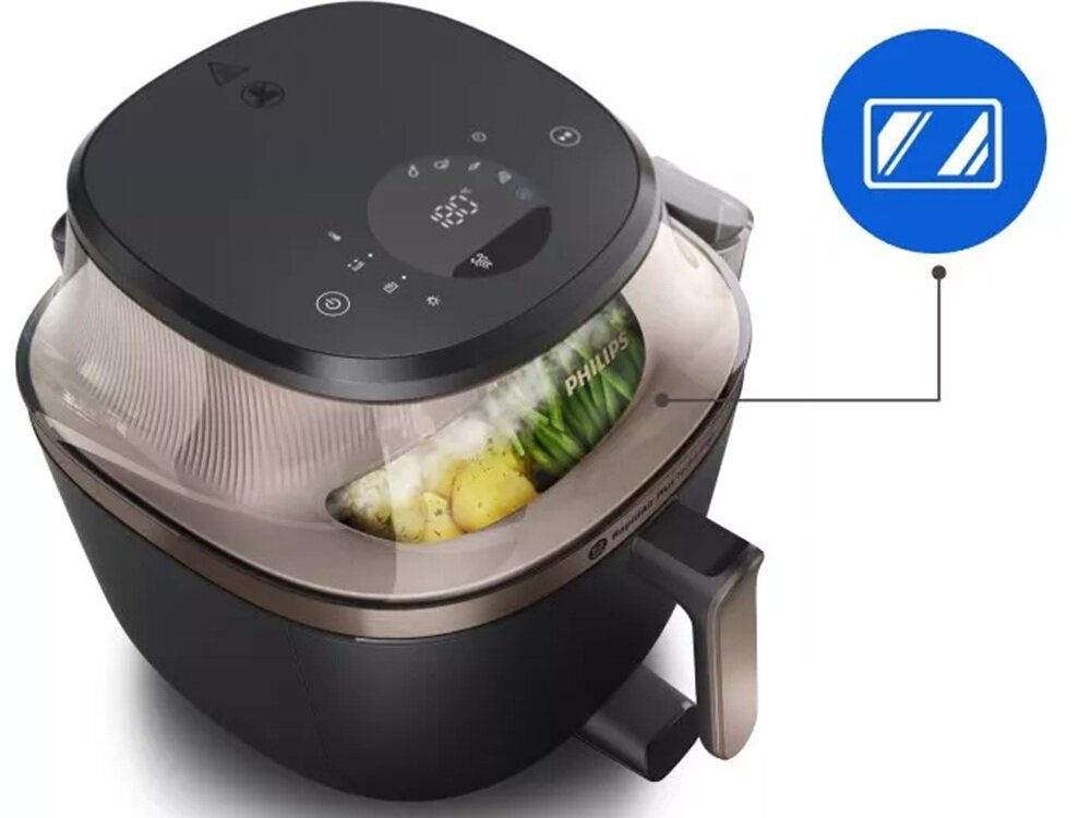Na zdjęciu widoczna jest beztłuszczowa frytkownica z przezroczystą pokrywą, przez którą widać warzywa. Na urządzeniu znajduje się logo \'PHILIPS\' oraz panel dotykowy z ikonami i wyświetlaczem cyfrowym.