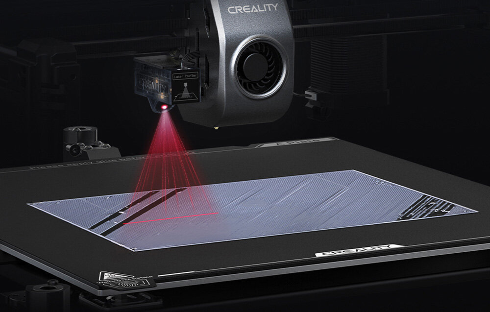 Obraz przedstawia drukarkę 3D z widocznym logo \'CREALITY\' na obudowie. Urządzenie emituje czerwony laser na powierzchnię roboczą.