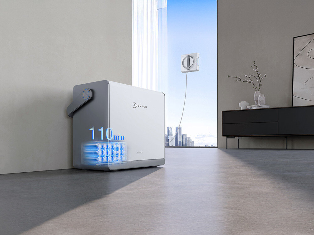 Na obrazie widoczny jest robot do mycia okien z logo ECOVACS, obok którego znajduje się napis \'110 min\'. W tle widać duże okno z widokiem na miasto oraz nowoczesne wnętrze z szafką i dekoracją.