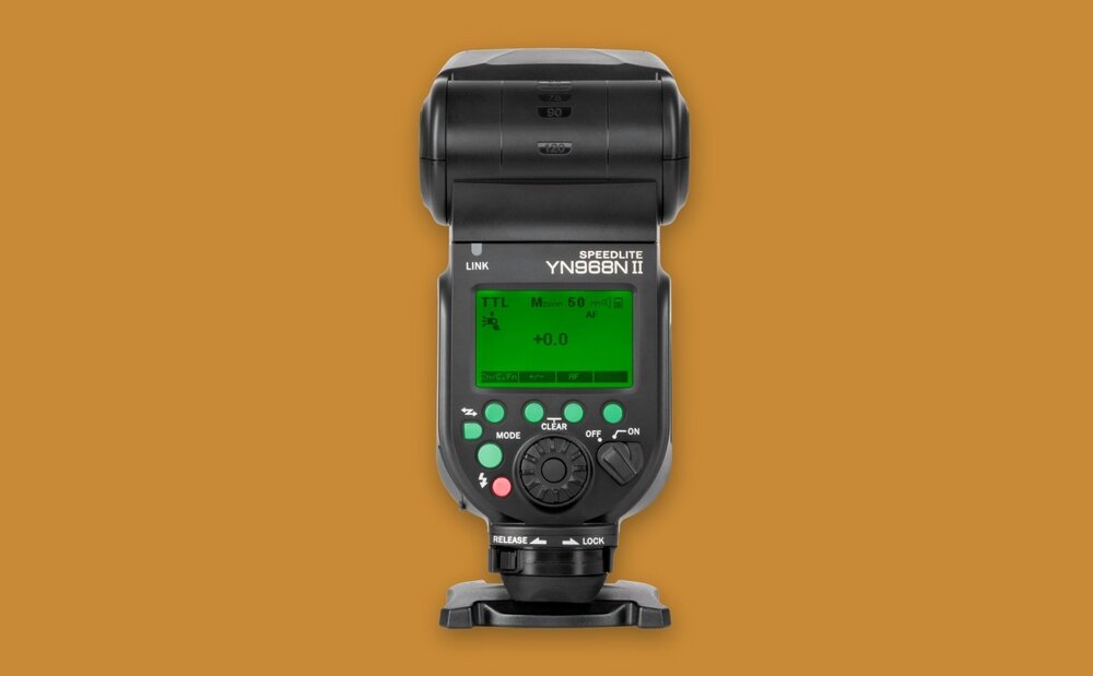 Lampa błyskowa z wyświetlaczem LCD pokazującym ustawienia takie jak TTL i moc błysku. Na obudowie widoczne są przyciski sterujące oraz napisy \'SPEEDLITE YN968N II\'.
