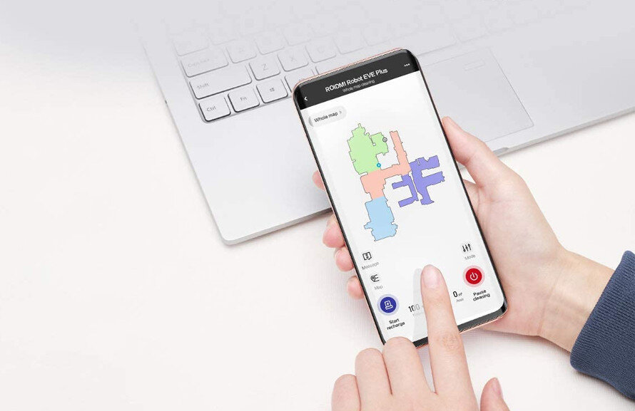 Osoba trzyma smartfon z aplikacją pokazującą mapę pomieszczeń w różnych kolorach. Na ekranie widoczny jest tekst \'ROIDMI Robot EVE Plus\'.