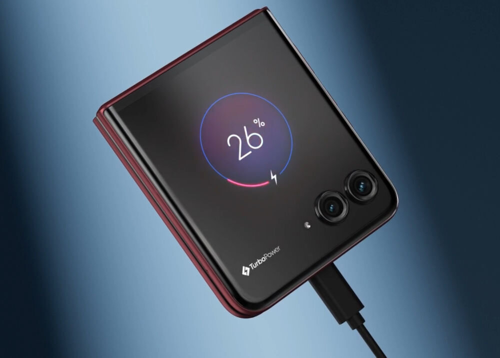 Złożony smartfon z widocznym ekranem pokazującym ikonę ładowania z napisem \'26%\'. Na obudowie znajduje się logo \'TurboPower\' oraz dwa obiektywy aparatu.