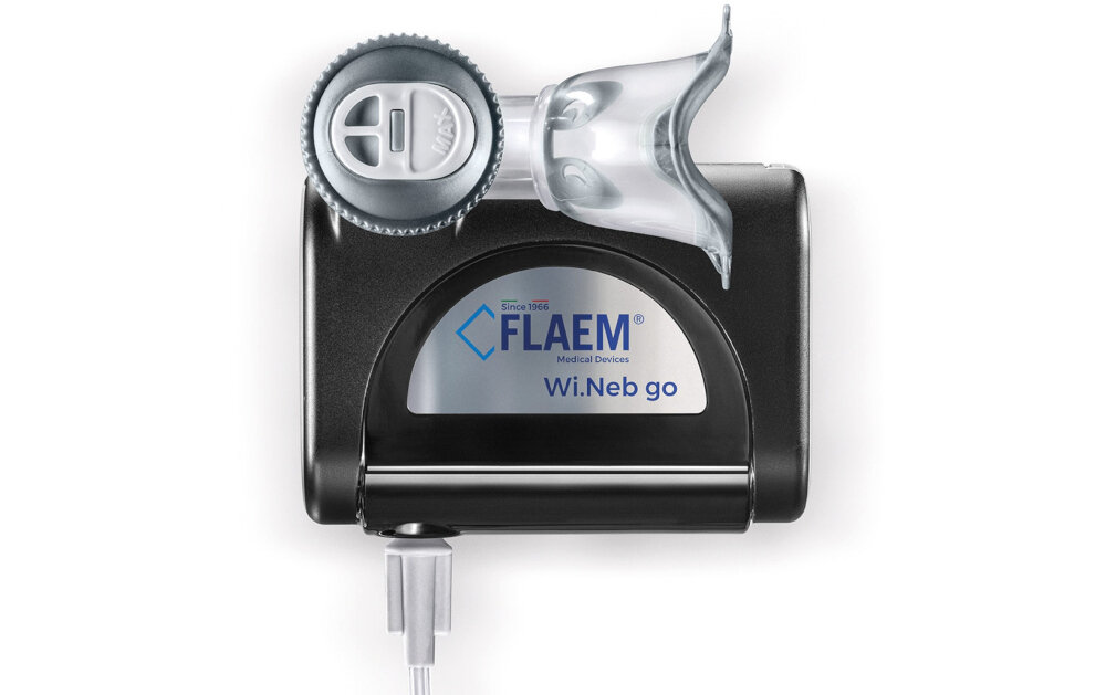 Na obrazie widoczny jest inhalator nebulizator pneumatyczny z logo \'FLAEM Medical Devices\' oraz napisem \'Wi.Neb go\'. Urządzenie ma czarną obudowę z przezroczystą częścią na górze.