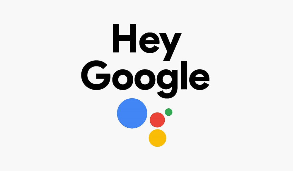 Na obrazie widnieje napis \'Hey Google\' oraz cztery kolorowe kropki w kolorach niebieskim, czerwonym, żółtym i zielonym.