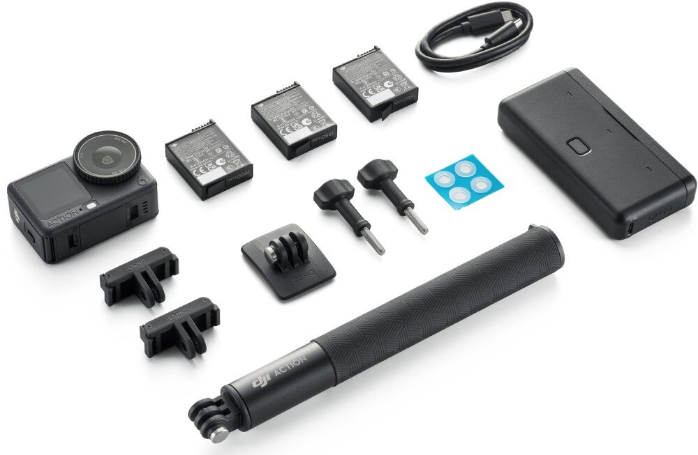 Na obrazie znajduje się zestaw akcesoriów do kamery sportowej, w tym kamera, trzy baterie, uchwyty montażowe, kabel, kijek do selfie z napisem \'DJI Action\' oraz etui. Widoczne są również śruby montażowe i małe naklejki ochronne.