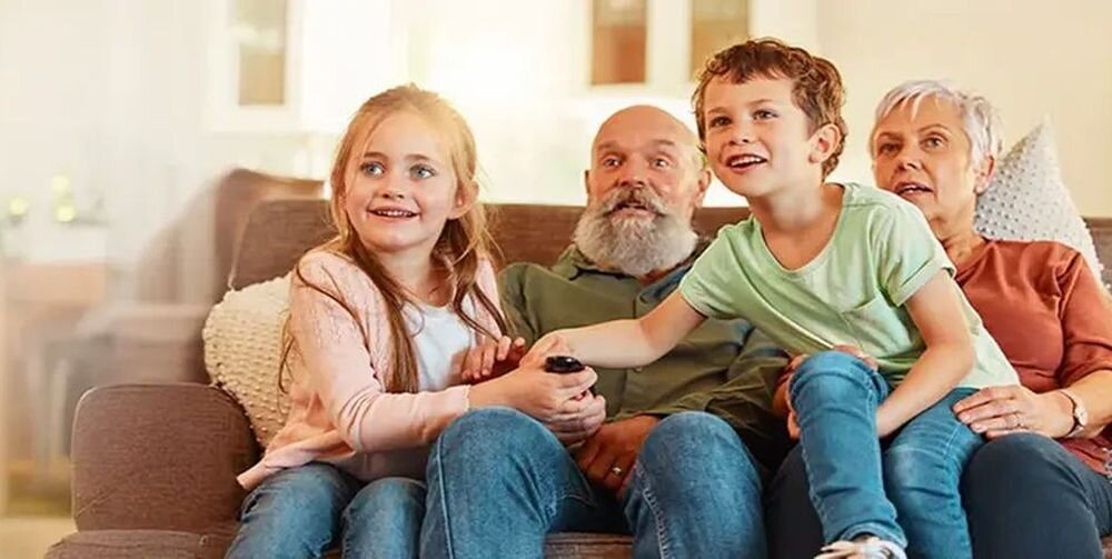 LG 43QNED7EB3C dostępność TV ułatwienia Color Adjustment Hearing Assist, rodzina siedząca na kanapie
