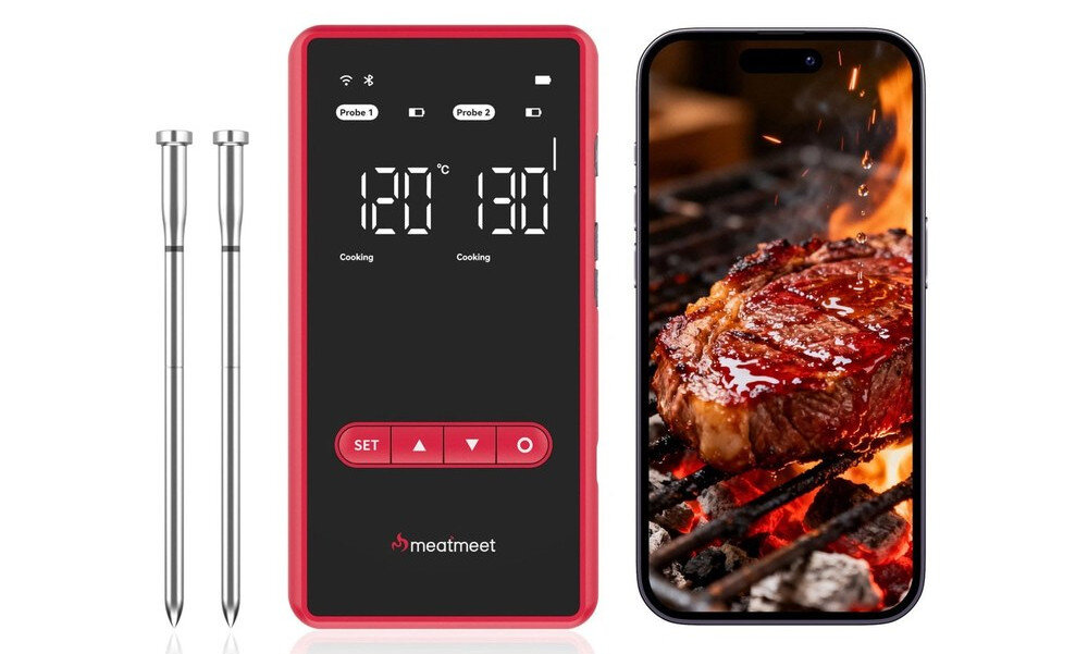 Na obrazie widoczny jest termometr do żywności z wyświetlaczem pokazującym temperatury 120°C i 130°C oraz dwa metalowe czujniki. Obok znajduje się telefon z wyświetlonym zdjęciem grillowanego steku na ruszcie z płomieniami w tle.