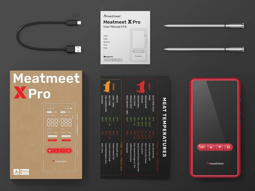 Na obrazie znajduje się zestaw termometru do żywności Meatmeet X Pro, w skład którego wchodzą: urządzenie z czerwonymi przyciskami, dwa metalowe czujniki, kabel USB, instrukcja obsługi oraz pudełko z napisem \'Meatmeet X Pro\'. Obok znajduje się karta z tabelą temperatur mięsa oznaczona jako \'MEAT TEMPERATURES\'.