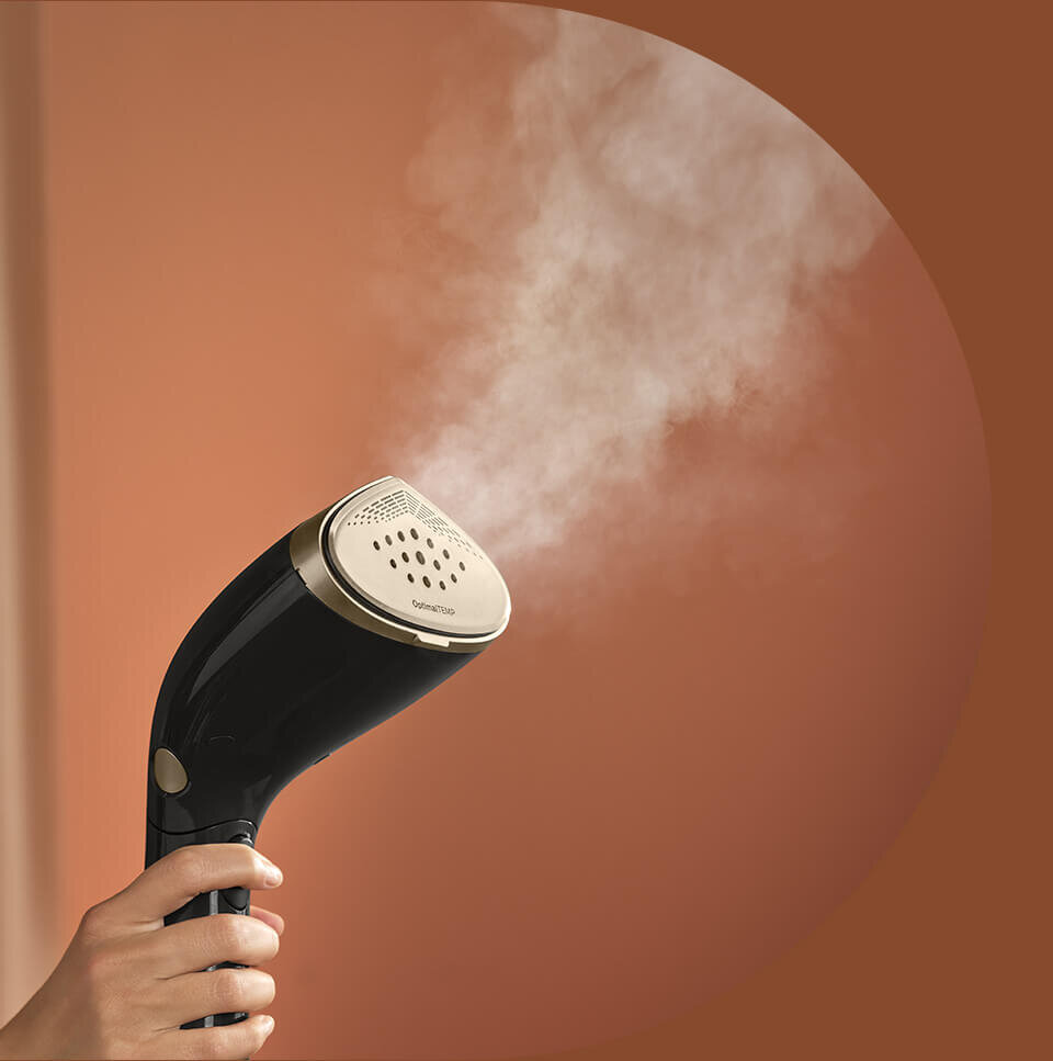 Osoba trzyma czarną parownicę do ubrań, z której wydobywa się para. Na urządzeniu widoczny jest napis \'OptimalTEMP\'.