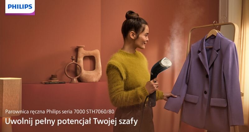 Osoba używa parownicy do ubrań na fioletowej marynarce wiszącej na wieszaku. Na obrazie widoczny jest tekst: \'Parownica ręczna Philips seria 7000 STH7060/80 Uwolnij pełny potencjał Twojej szafy\'.