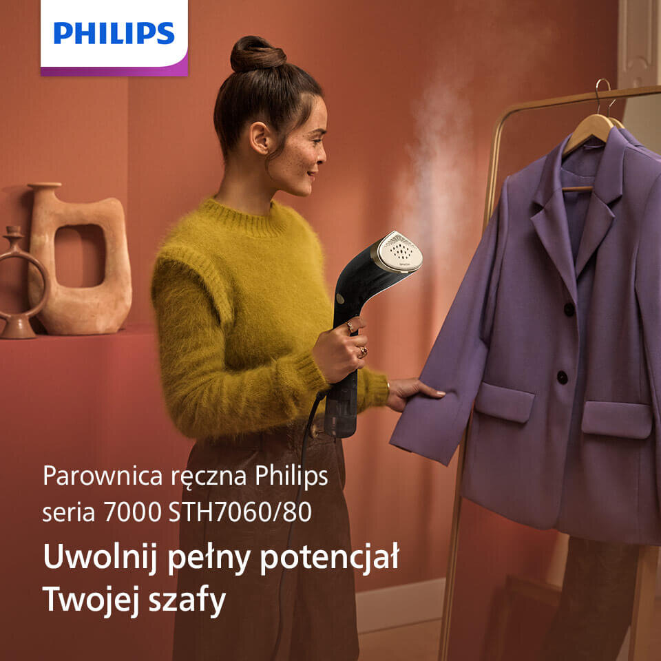 Osoba używa parownicy do ubrań, kierując parę na fioletowy płaszcz wiszący na wieszaku. Widoczny jest tekst: \'Parownica ręczna Philips seria 7000 STH7060/80 Uwolnij pełny potencjał Twojej szafy\'.