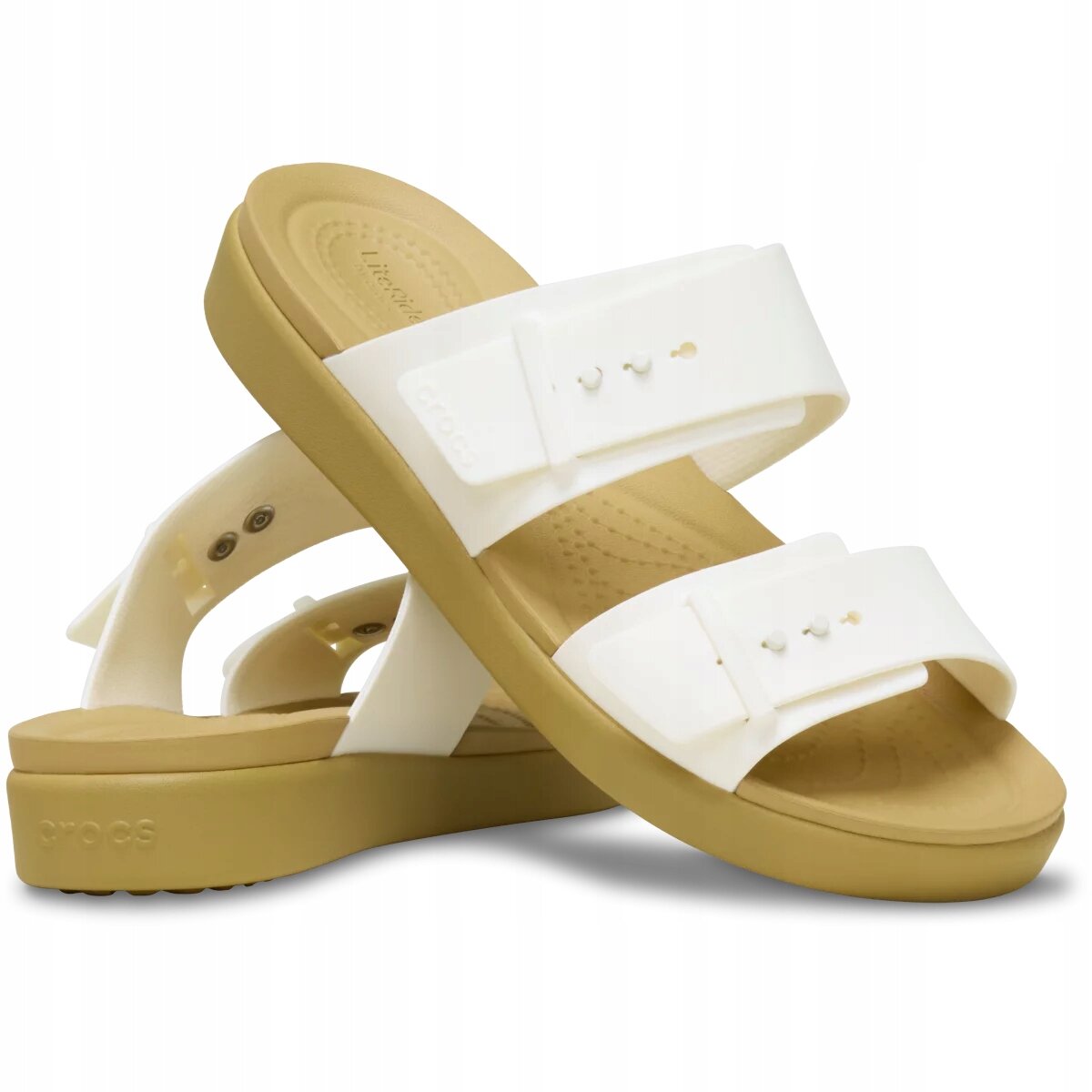 Na obrazie widoczne są białe sandały z grubą, beżową podeszwą. Na pasku znajduje się napis \'Crocs\'.