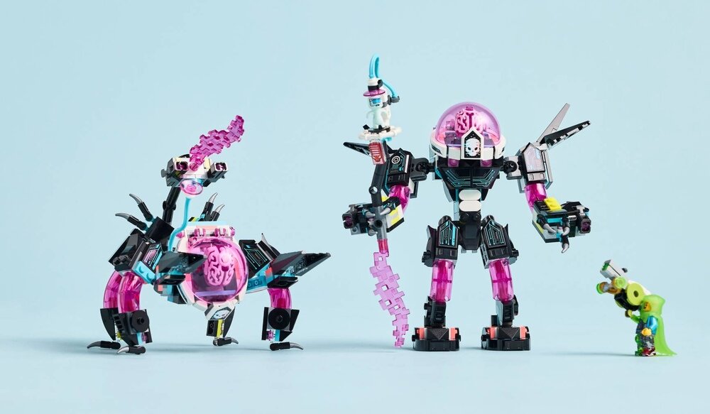 Na jasnoniebieskim tle znajdują się trzy konstrukcje z klocków LEGO: duży mech z różową kopułą, mniejszy mechaniczny stwór oraz zielona postać z małym akcesorium. Konstrukcje mają elementy w kolorach czarnym, różowym i niebieskim.