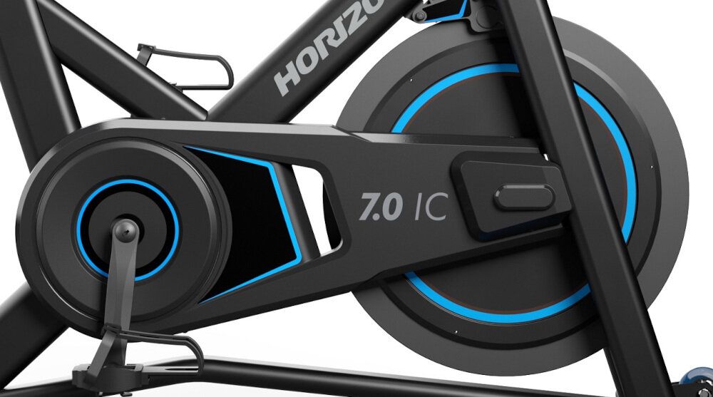 Zbliżenie na mechanizm roweru spinningowego z widocznym napisem \'HORIZON\' oraz oznaczeniem modelu \'7.0 IC\'. Elementy konstrukcji są w kolorze czarnym z niebieskimi akcentami.