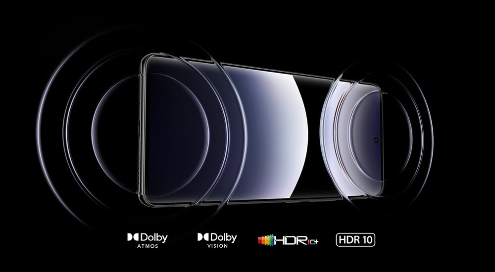 Obraz przedstawia smartfon z widocznym ekranem, otoczony efektami graficznymi symbolizującymi dźwięk i obraz. Na dole znajdują się logotypy: Dolby Atmos, Dolby Vision, HDR10+ i HDR10.