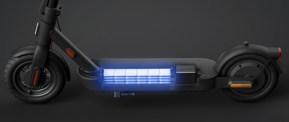 Obraz przedstawia czarną hulajnogę elektryczną z widocznym podświetleniem baterii na podeście. Hulajnoga ma solidne opony i nowoczesny design.
