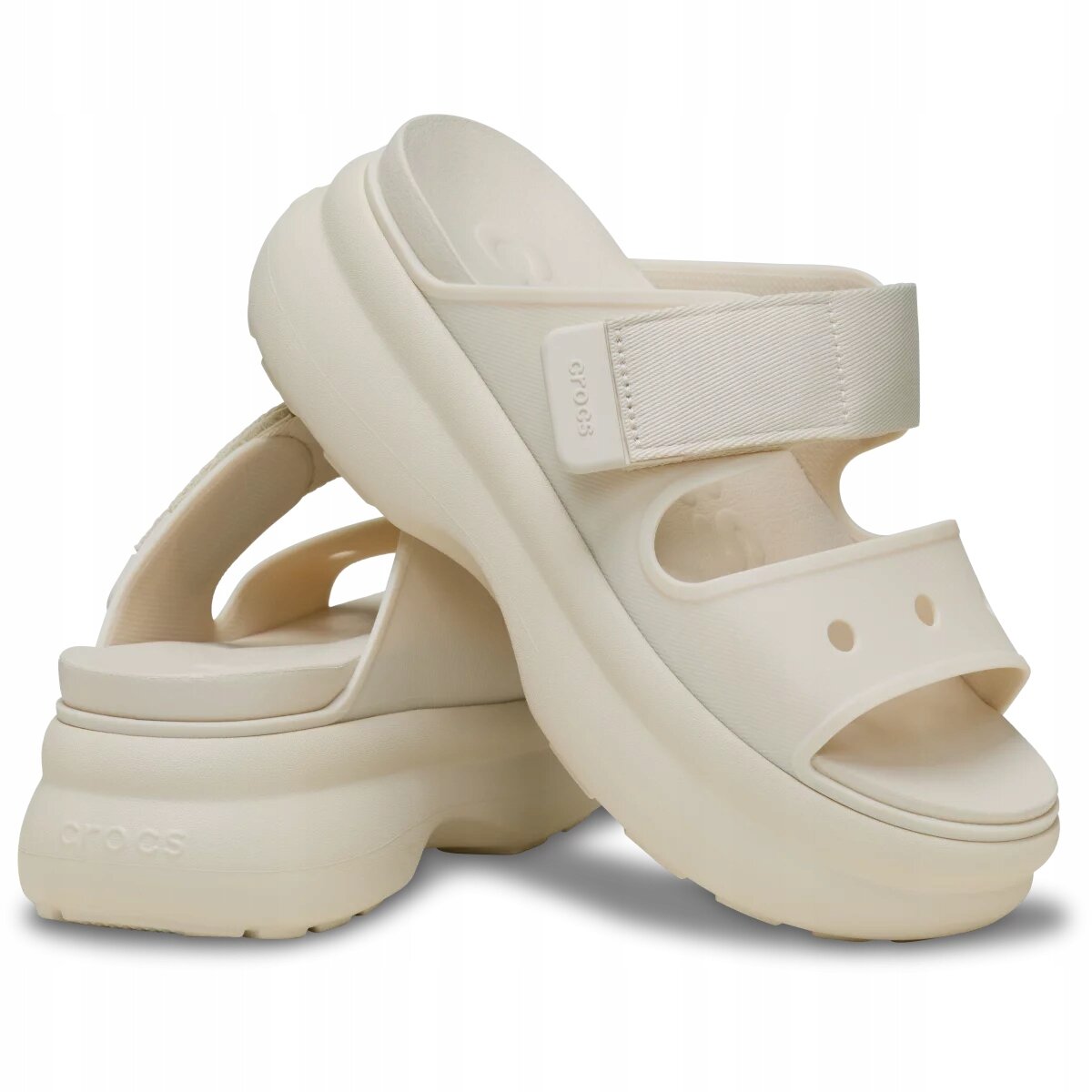 Na obrazie widoczne są beżowe sandały z grubą podeszwą i dwoma paskami, z których jeden ma napis \'crocs\'.
