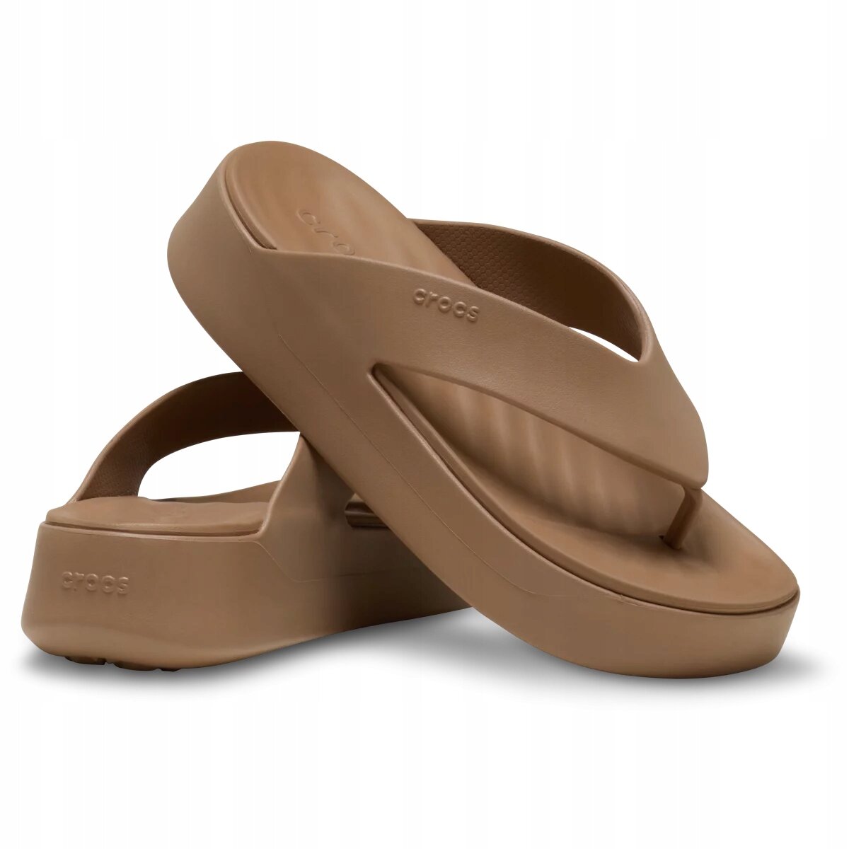 Brązowe klapki typu japonki na platformie z widocznym logo \'crocs\' na pasku. Obuwie ma prosty, nowoczesny design z grubą podeszwą.