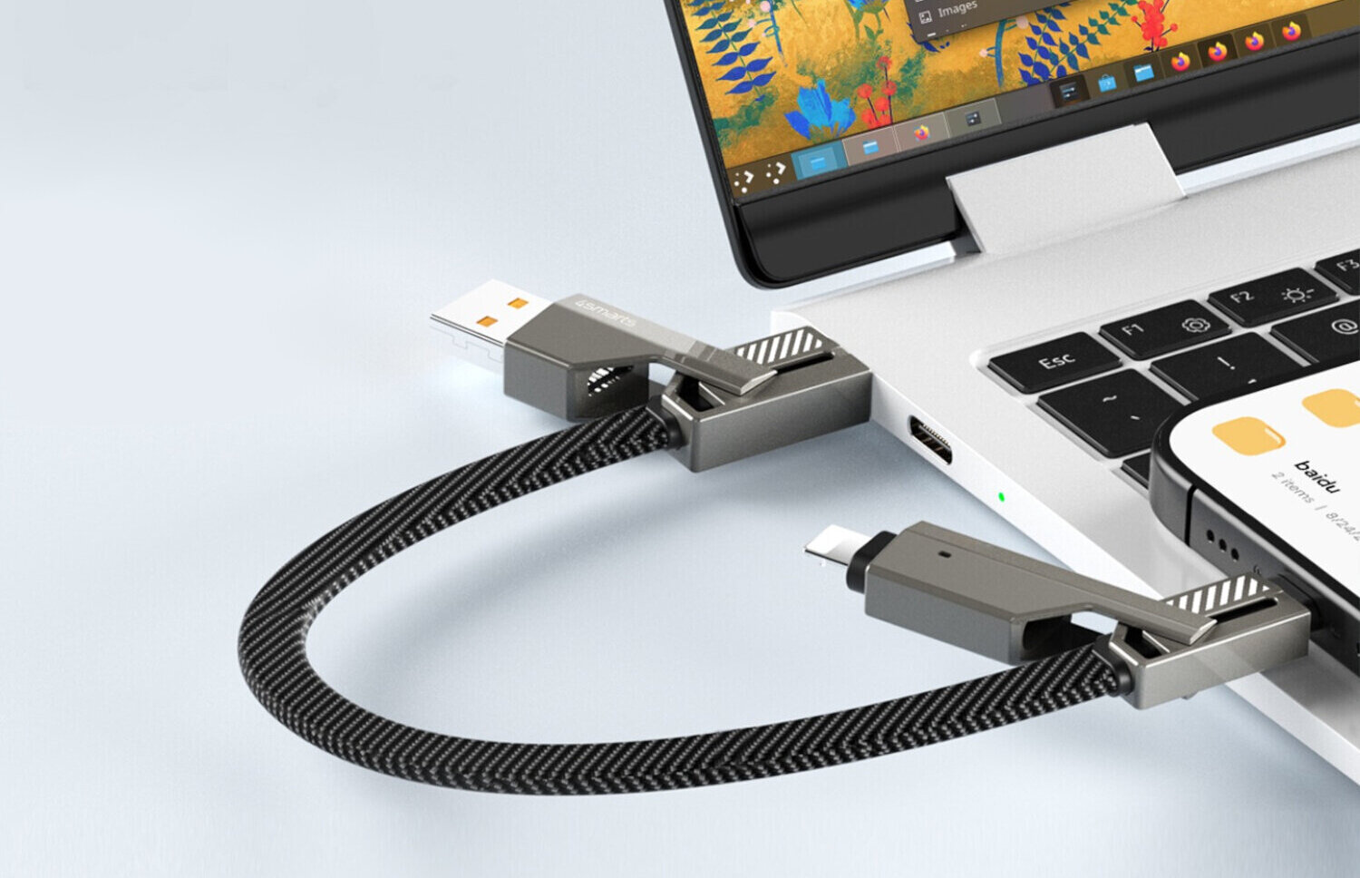 Na obrazie widać laptopa z podłączonym kablem USB, który ma końcówki USB-A i USB-C/Lightning. Kabel jest grafitowy i ma plecioną strukturę.