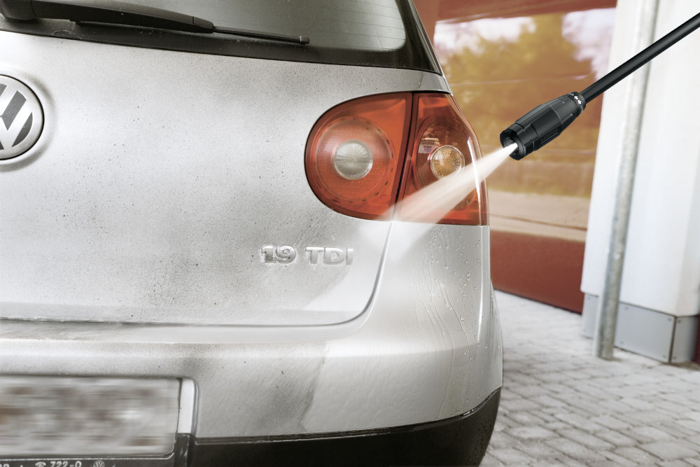 Samochód jest myty strumieniem wody z myjki ciśnieniowej. Na tylnej klapie widoczne są oznaczenia \'1.9 TDI\' oraz logo producenta samochodu.