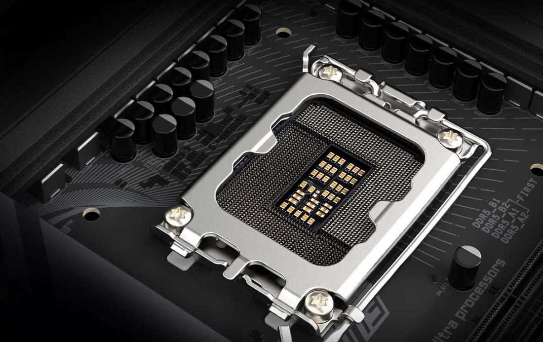 Zbliżenie na gniazdo procesora na płycie głównej z widocznymi pinami i metalowym mocowaniem. W tle widać elementy elektroniczne oraz napisy: \'DDR5\' i \'Ultra processors\'.