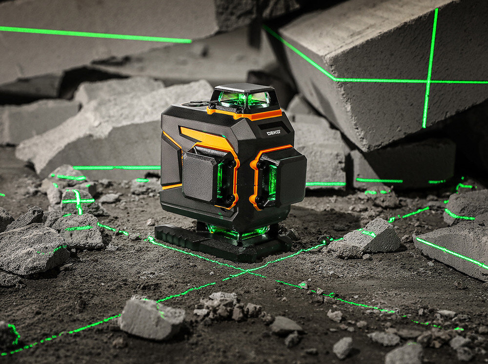 Laser krzyżowy z widocznymi zielonymi liniami na tle betonowych bloków. Na urządzeniu widoczne jest logo \'DEKO\'.