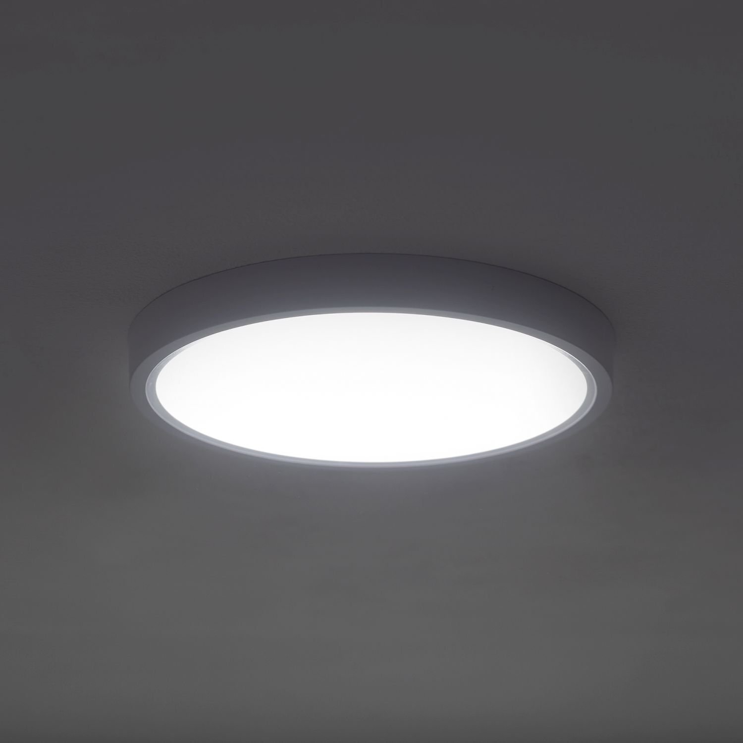 Na obrazie widoczny jest okrągły plafon LED emitujący jasne światło, zamontowany na suficie. Plafon ma prosty, nowoczesny design z ciemną obwódką.