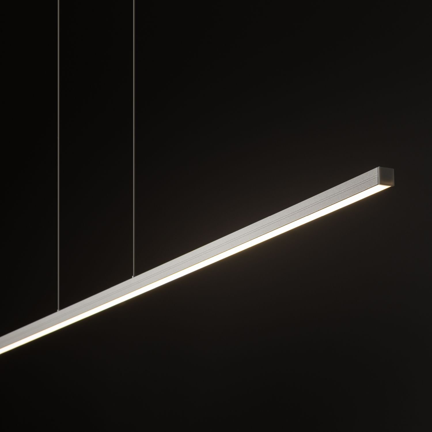 Lampa wisząca LED o prostokątnym kształcie, zawieszona na dwóch cienkich przewodach, emitująca jasne światło na ciemnym tle.