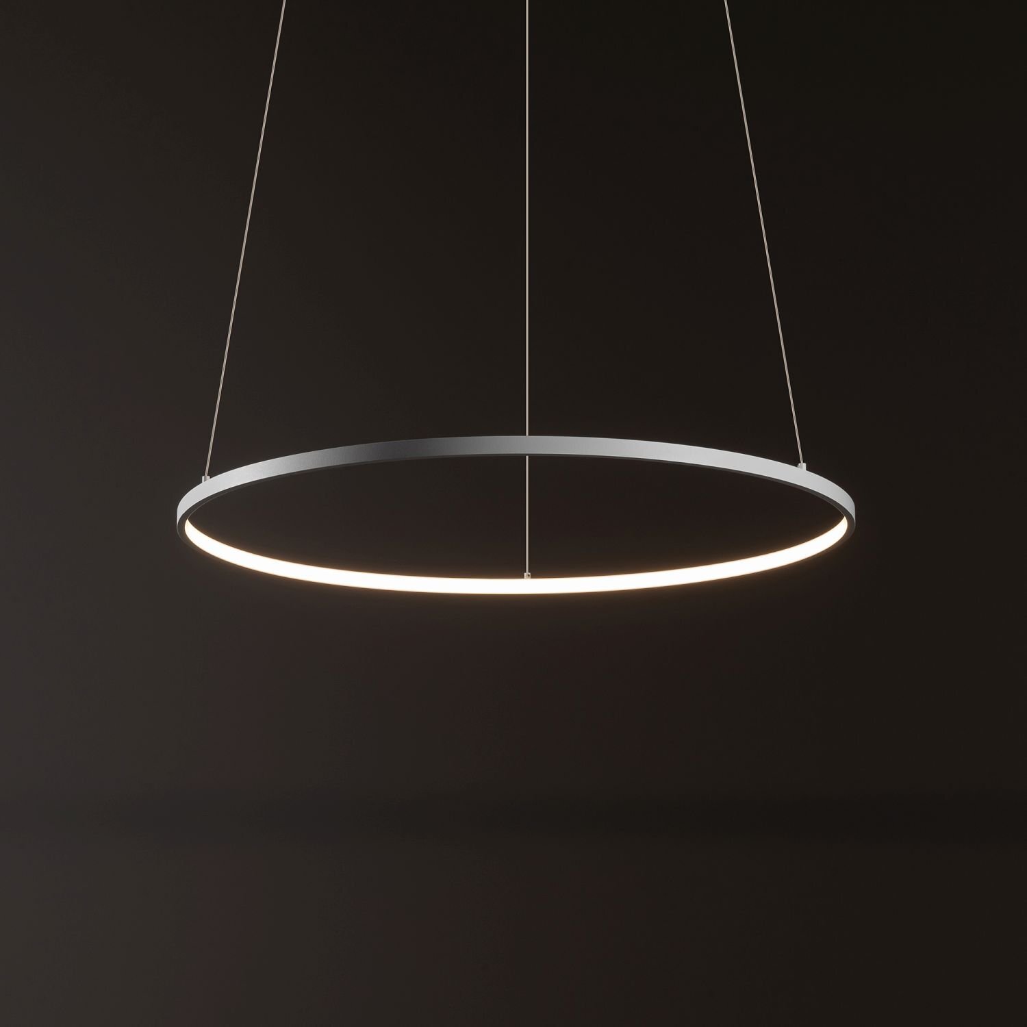Na ciemnym tle wisi okrągła lampa LED o nowoczesnym designie, zawieszona na cienkich linkach. Lampa emituje delikatne, białe światło.