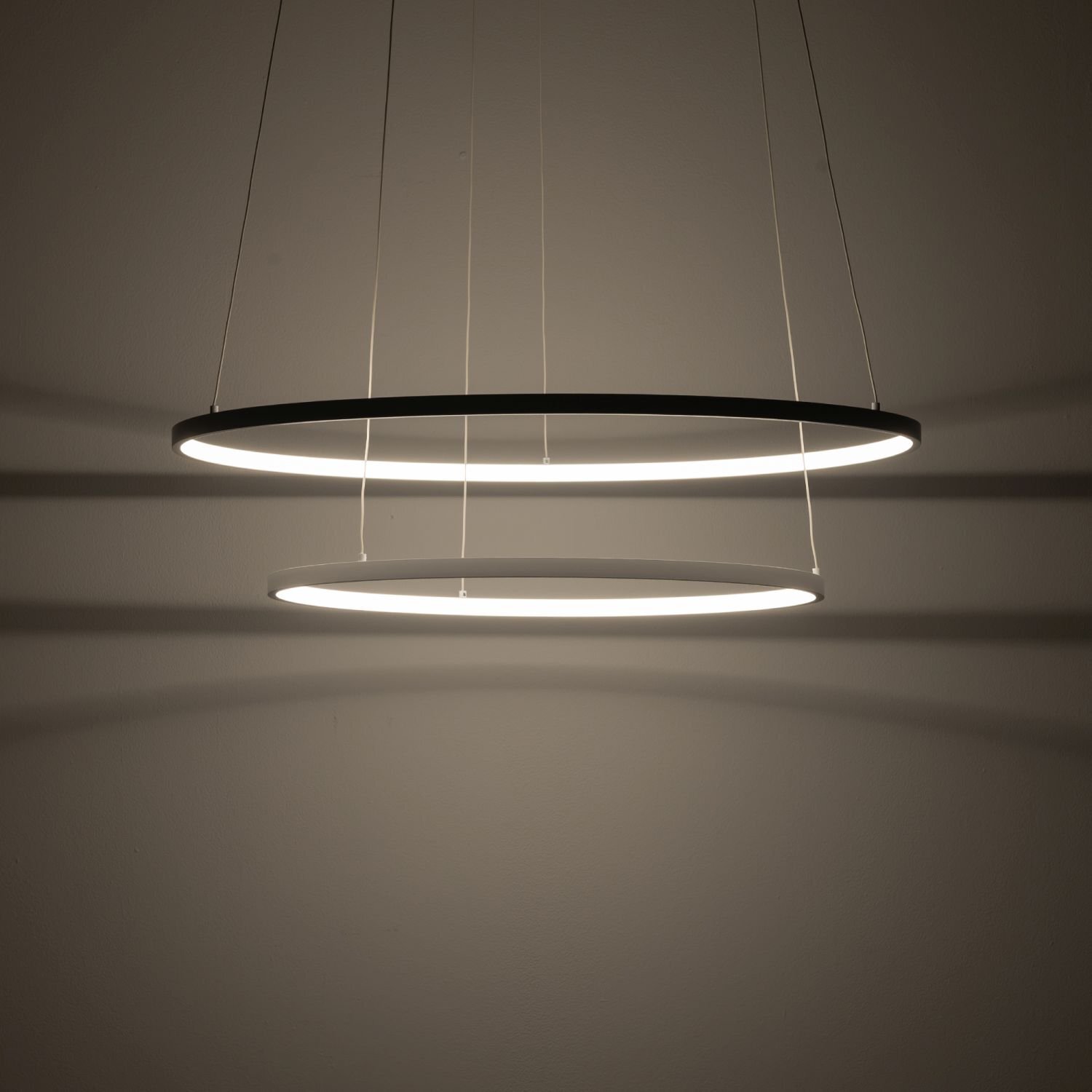 Na obrazie widoczne są dwie okrągłe, wiszące lampy LED emitujące jasne światło. Lampy są zawieszone na cienkich przewodach i tworzą nowoczesny, minimalistyczny wygląd.