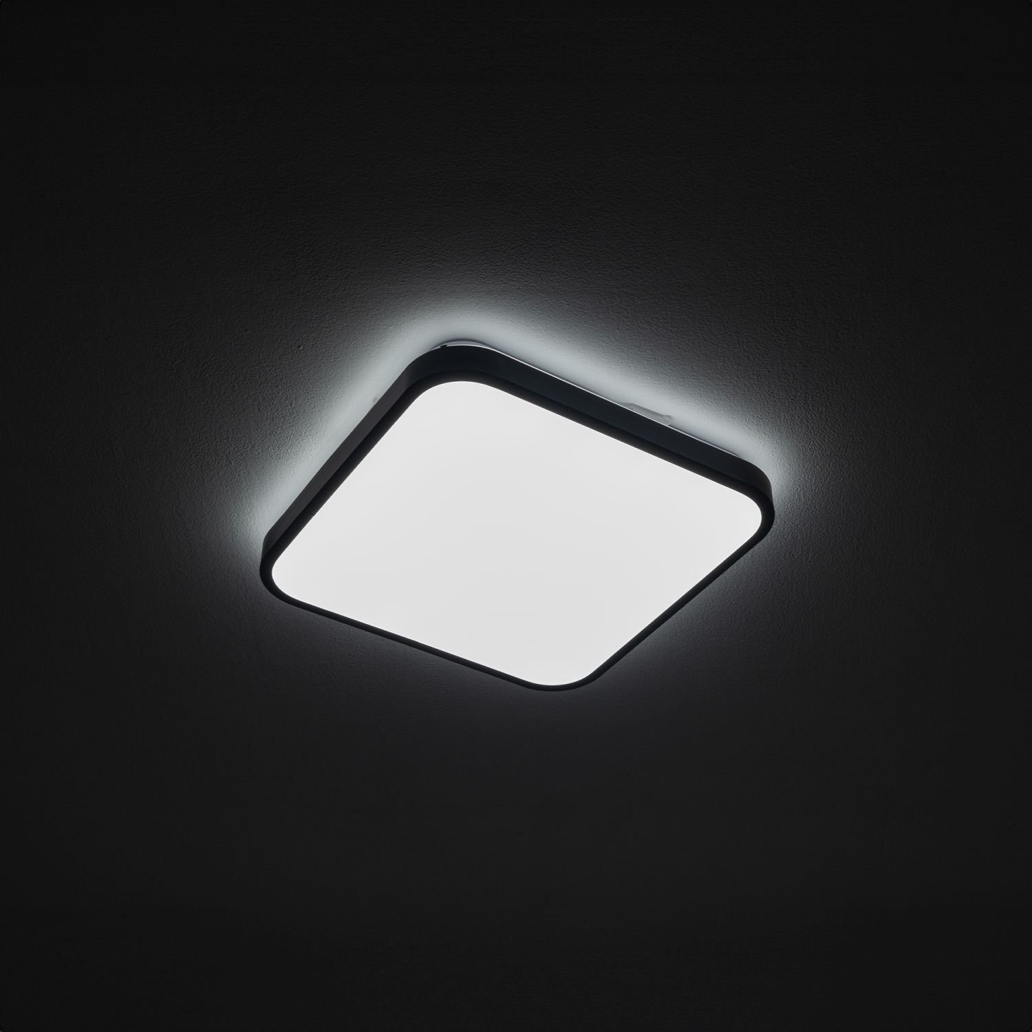 Kwadratowy plafon LED o nowoczesnym designie, emitujący jasne, równomierne światło. Lampa jest zamontowana na suficie w ciemnym pomieszczeniu.