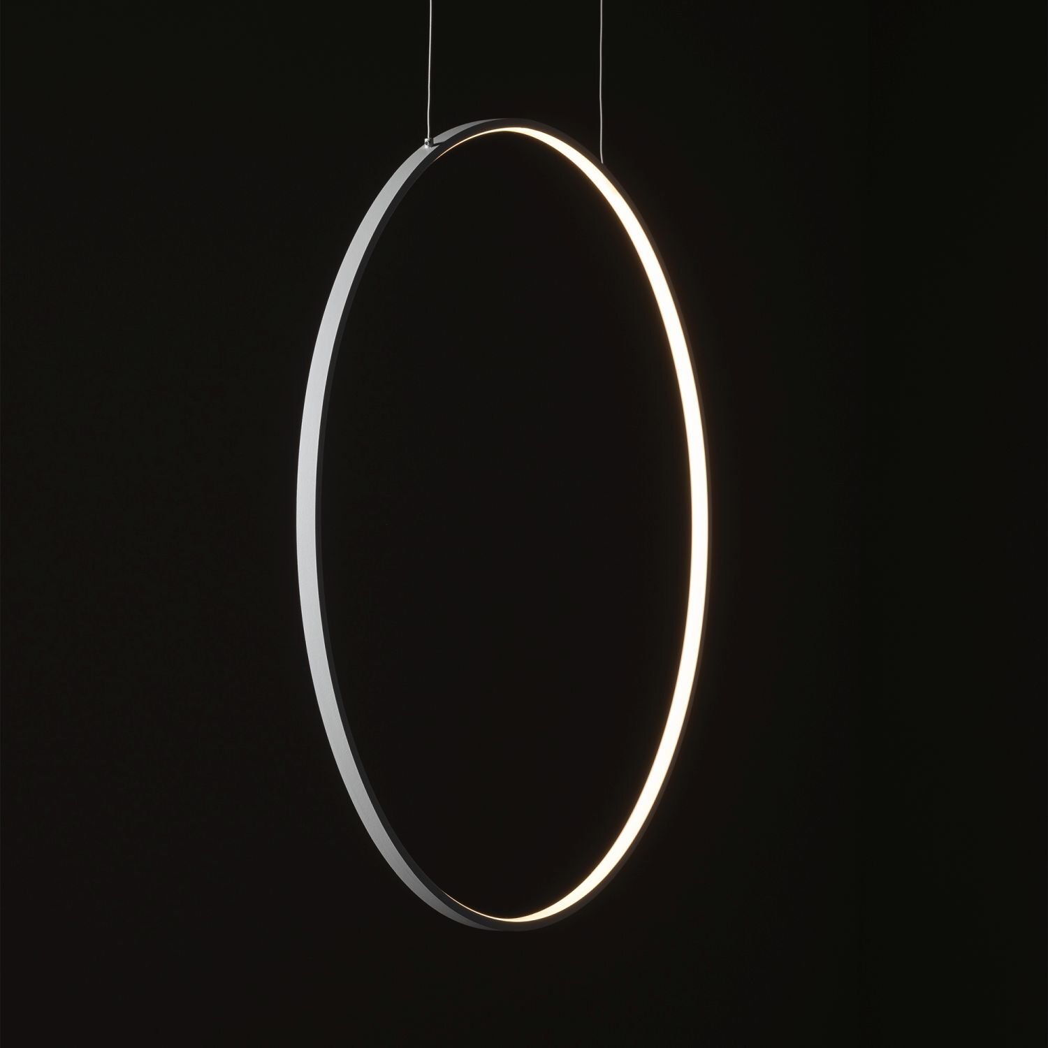 Na obrazie widoczna jest nowoczesna, wisząca lampa LED w kształcie okręgu, emitująca jasne światło. Tło jest ciemne, co podkreśla minimalistyczny design lampy.