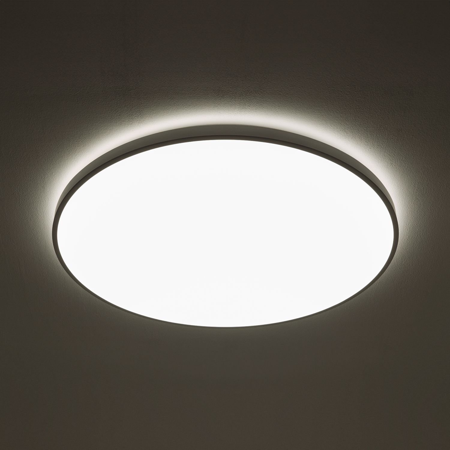 Okrągła lampa sufitowa emitująca jasne, równomierne światło, zamontowana na suficie. Wokół lampy widoczna jest delikatna poświata na suficie.