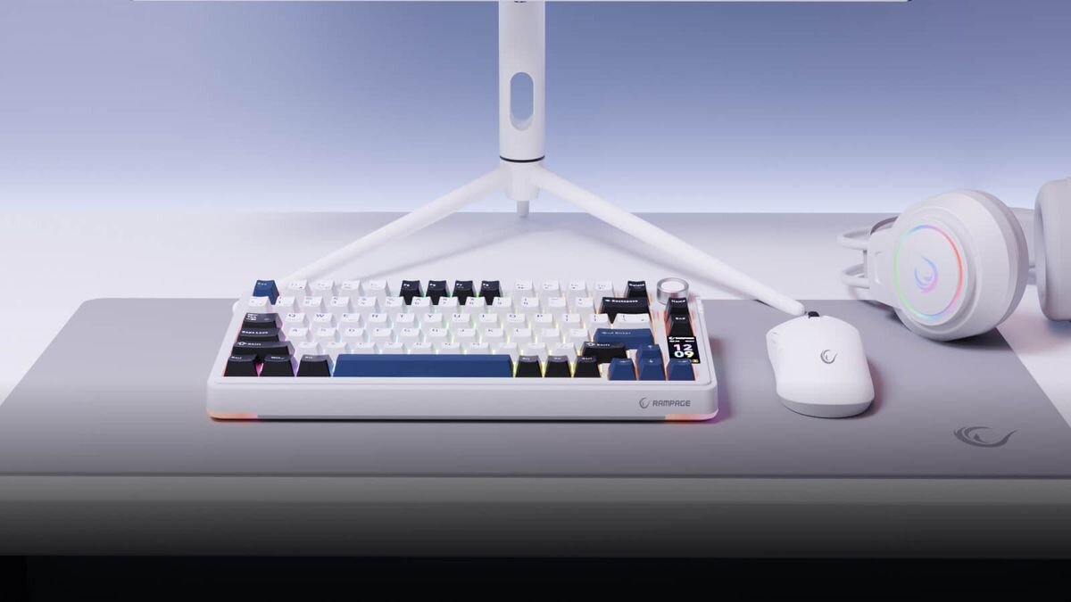 Na biurku znajduje się biała klawiatura mechaniczna z podświetleniem RGB, obok której leży biała mysz i słuchawki. Na klawiaturze widoczne jest logo \'RAMPAGE\'.