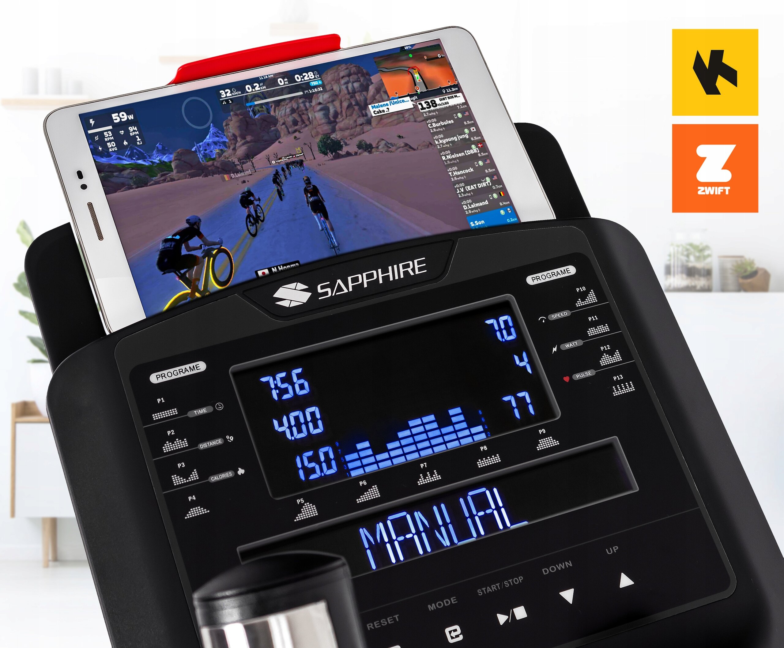 Na zdjęciu widoczny jest panel sterowania orbitreka z logo SAPPHIRE, na którym znajduje się tablet z aplikacją do treningu rowerowego. Obok panelu widoczne są dwa logotypy aplikacji: K i ZWIFT.
