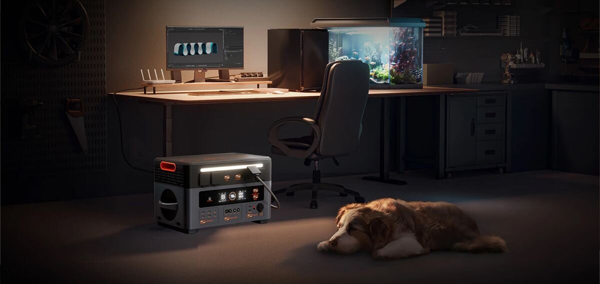 Stacja zasilania OSCAL PowerMax 2400 Pro 2016Wh, LCD, ekran, parametry, odczyt, PowerMax 2400 Pro w ciemnym pomieszczeniu, obok śpiący pies i dwa świecące monitory.