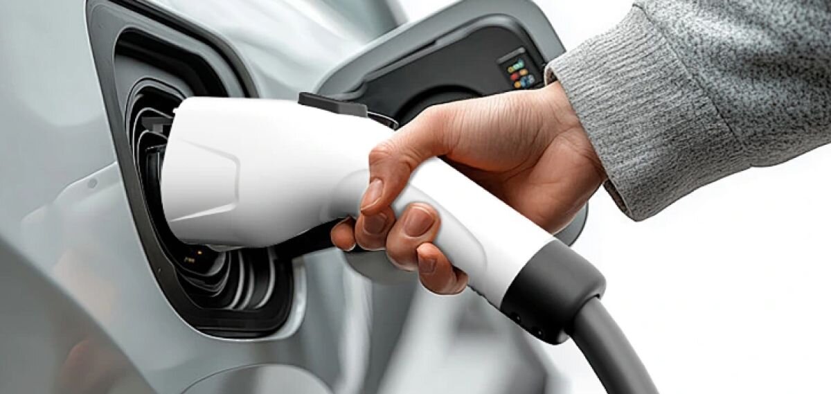 Ładowarka do samochodu elektrycznego OSCAL EV7000 7000W 32A, dłoń, wtyczka, gniazdo, ładowanie, Dłoń wkłada białą wtyczkę przewodu w gniazdo ładowania samochodu.