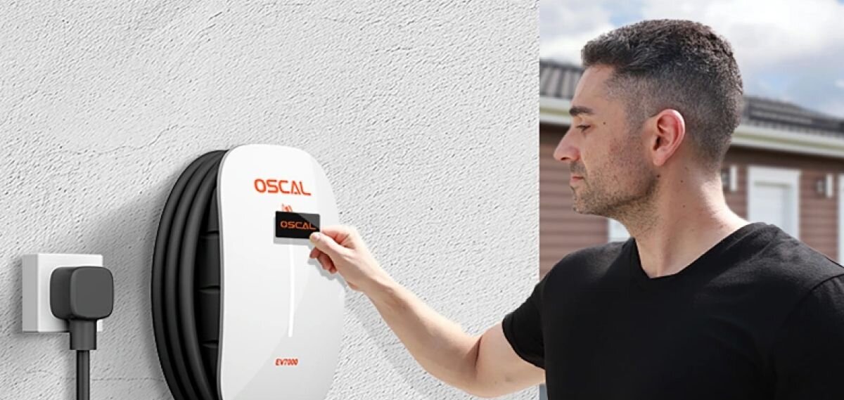Ładowarka do samochodu elektrycznego OSCAL EV7000 7000W 32A, mężczyzna, panel, ładowarka, ściana, Mężczyzna dotyka czarnego panelu ładowarki Oscal EV7000 zamontowanej na ścianie.