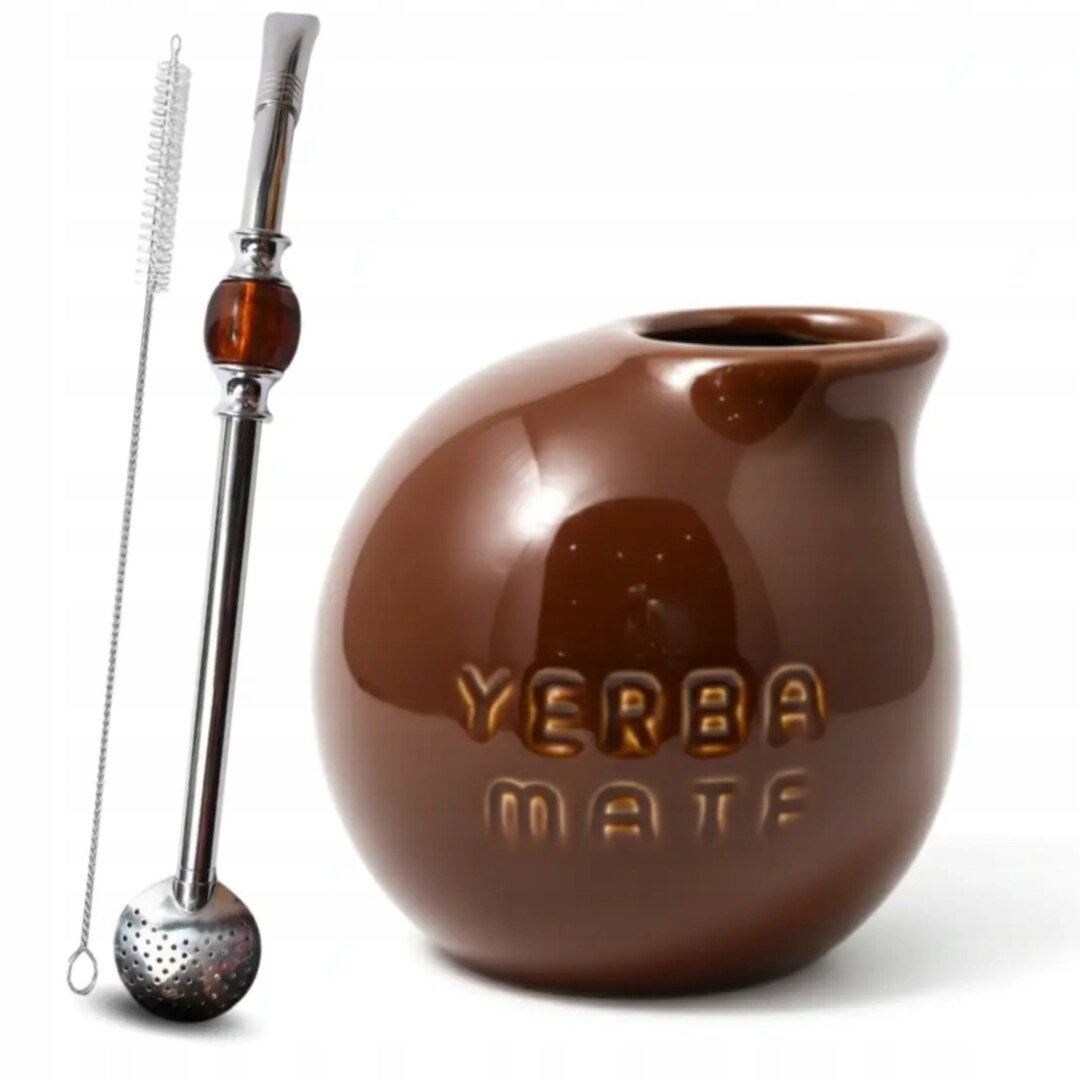 Na obrazie widoczny jest brązowy kubek o kształcie kuli z napisem \'YERBA MATE\' oraz metalowa bombilla z sitkiem i szczoteczką do czyszczenia.