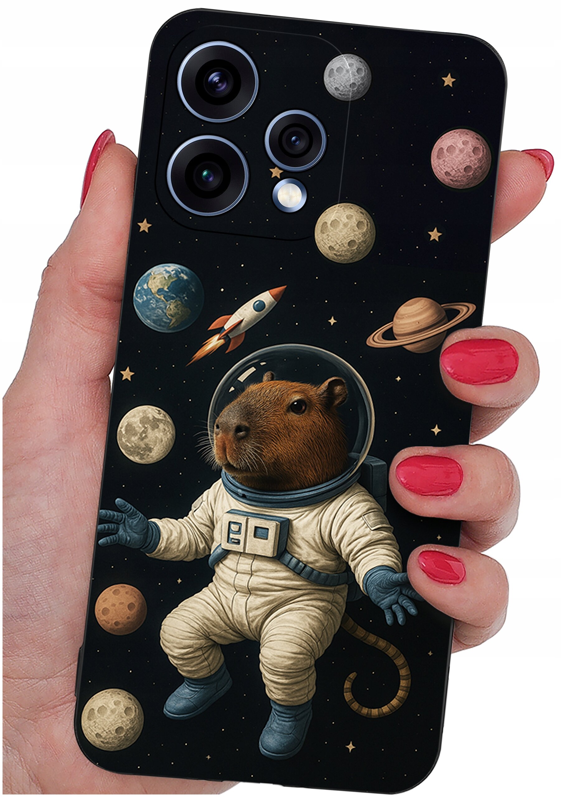 Etui na telefon z motywem kosmicznym, przedstawiające kapibarę w skafandrze astronauty otoczoną planetami i rakietą. Etui trzymane jest w dłoni z pomalowanymi na czerwono paznokciami.