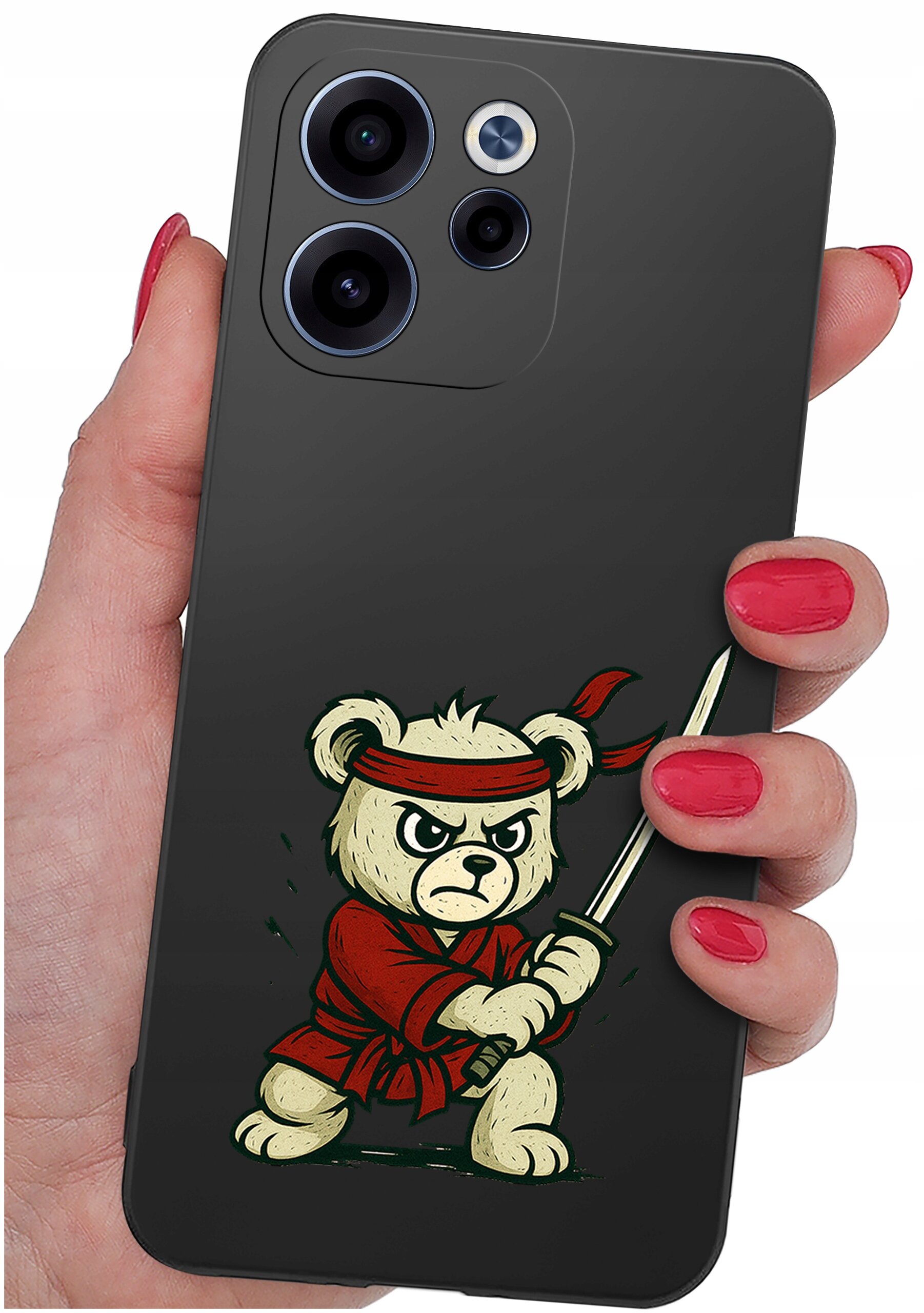 Osoba trzyma telefon z etui przedstawiającym rysunkowego misia w czerwonym stroju i opasce, trzymającego miecz. Etui jest ciemne, a paznokcie osoby są pomalowane na czerwono.