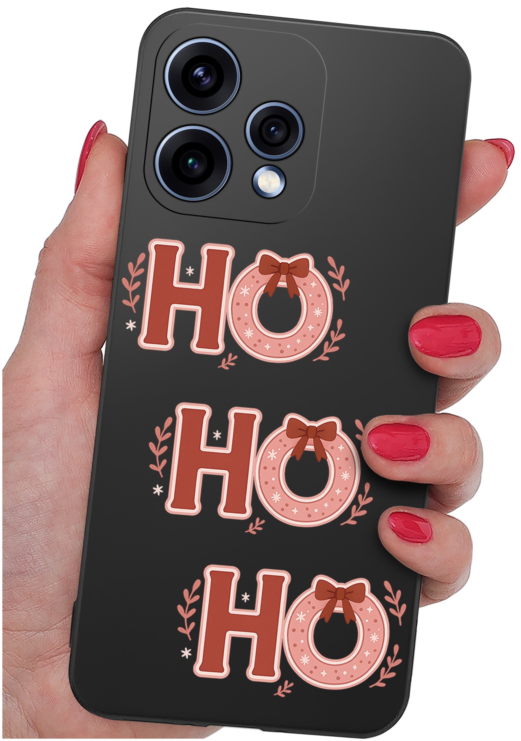 Osoba trzyma telefon w czarnym etui z napisem \'HO HO HO\' ozdobionym gałązkami i kokardkami. Etui ma wycięcia na trzy obiektywy aparatu i lampę błyskową.