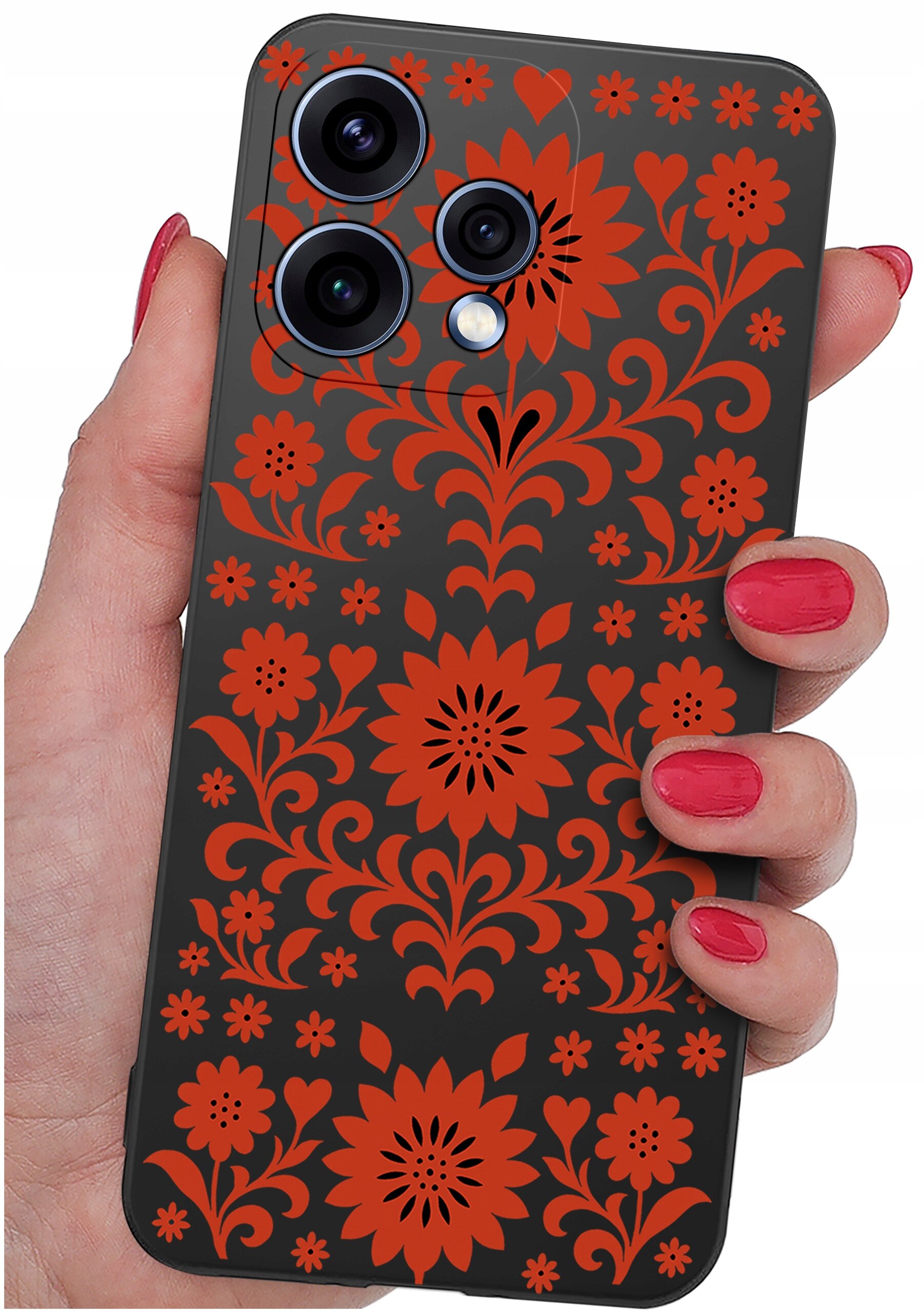 Etui na telefon z czarnym tłem ozdobione czerwonymi, kwiatowymi wzorami, trzymane w dłoni z pomalowanymi na czerwono paznokciami.