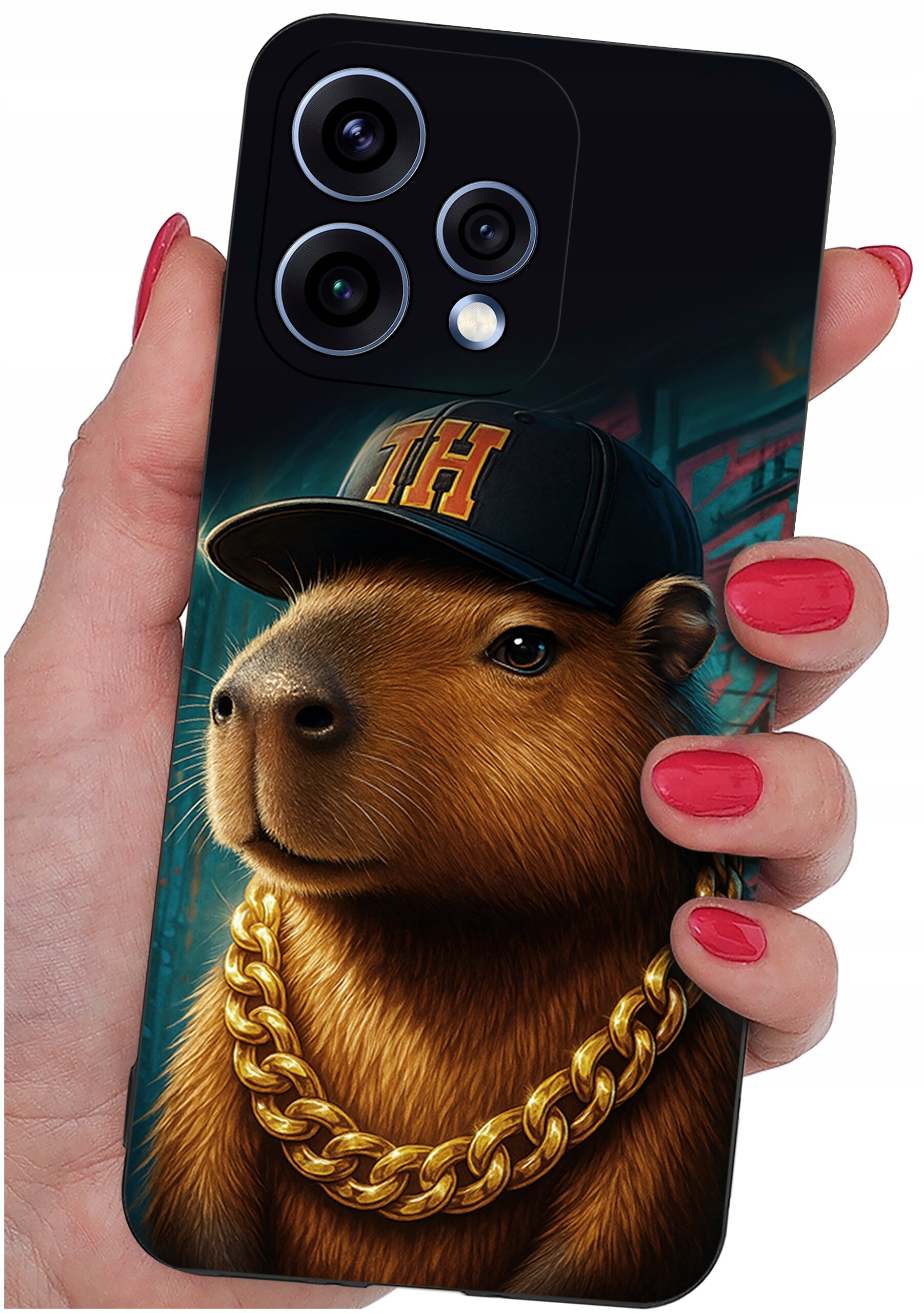 Etui na telefon z grafiką przedstawiającą kapibarę w czapce z literami \'TH\' i złotym łańcuchem. Etui trzymane jest w dłoni z pomalowanymi na czerwono paznokciami.