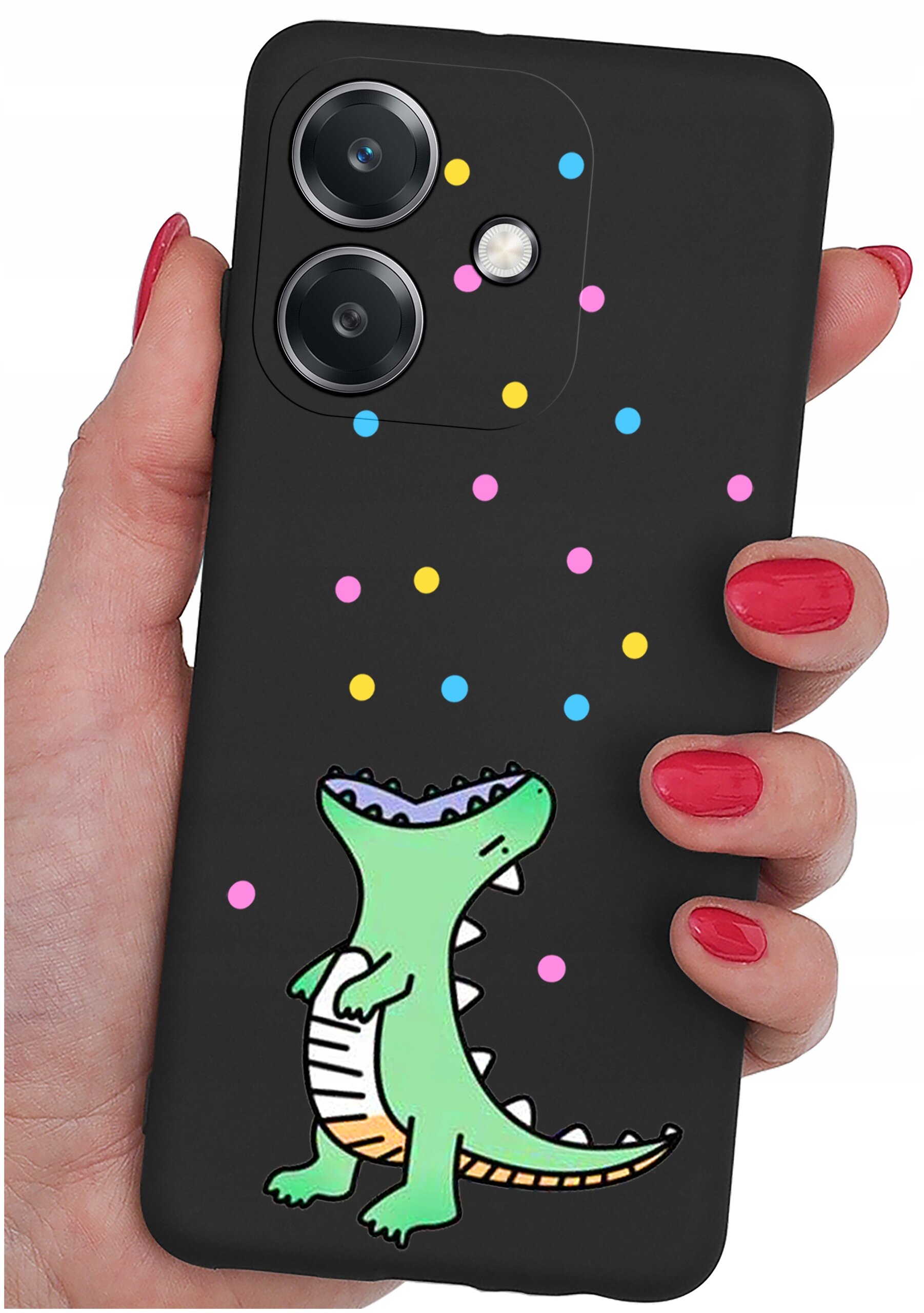 Czarne etui na telefon z kolorowym rysunkiem zielonego dinozaura i wielobarwnymi kropkami. Etui trzymane jest w dłoni z pomalowanymi na czerwono paznokciami.