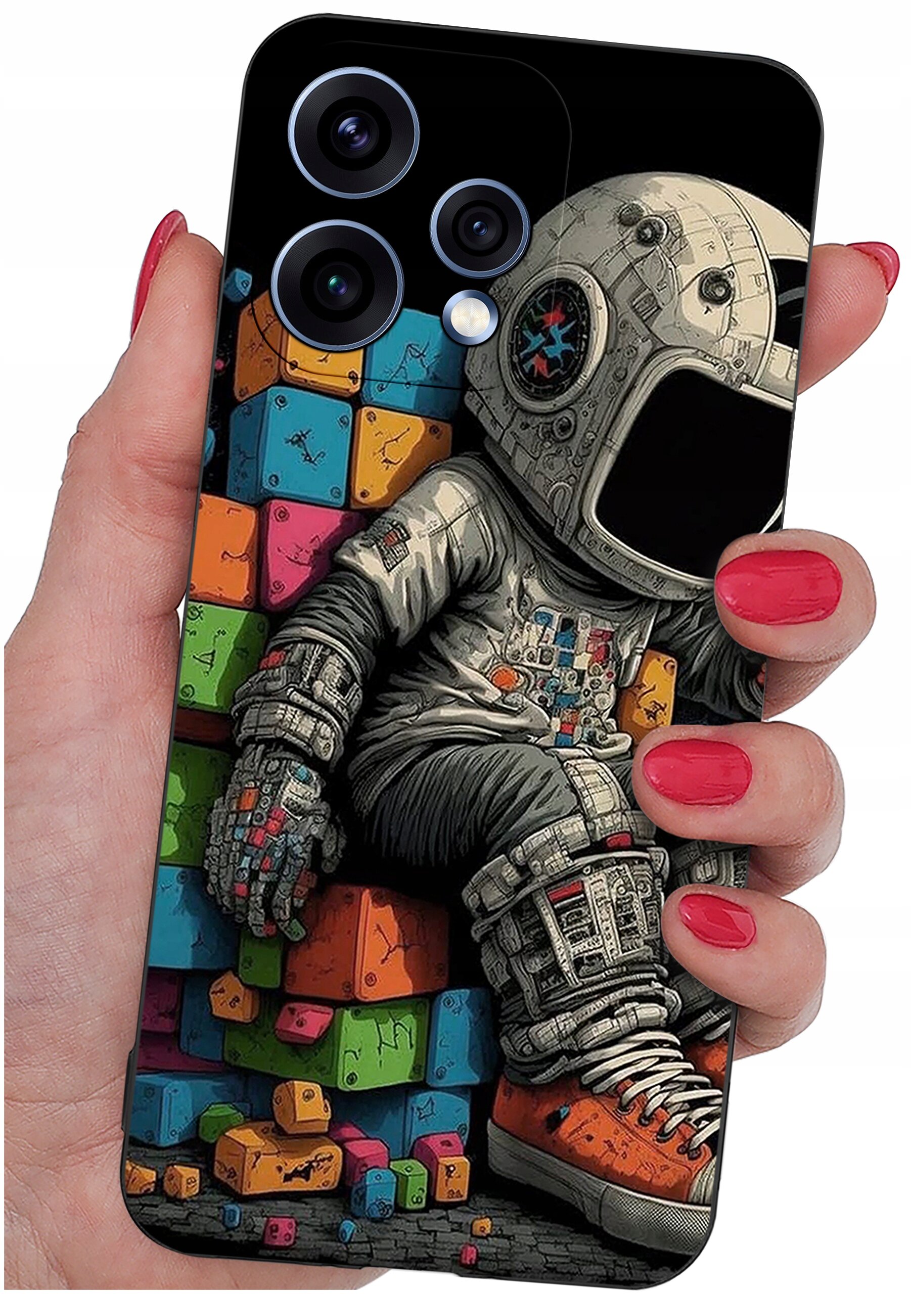 Etui na telefon z kolorowym wzorem przedstawiającym astronautę siedzącego na tle kolorowych klocków. Etui trzymane jest w dłoni z pomalowanymi na czerwono paznokciami.