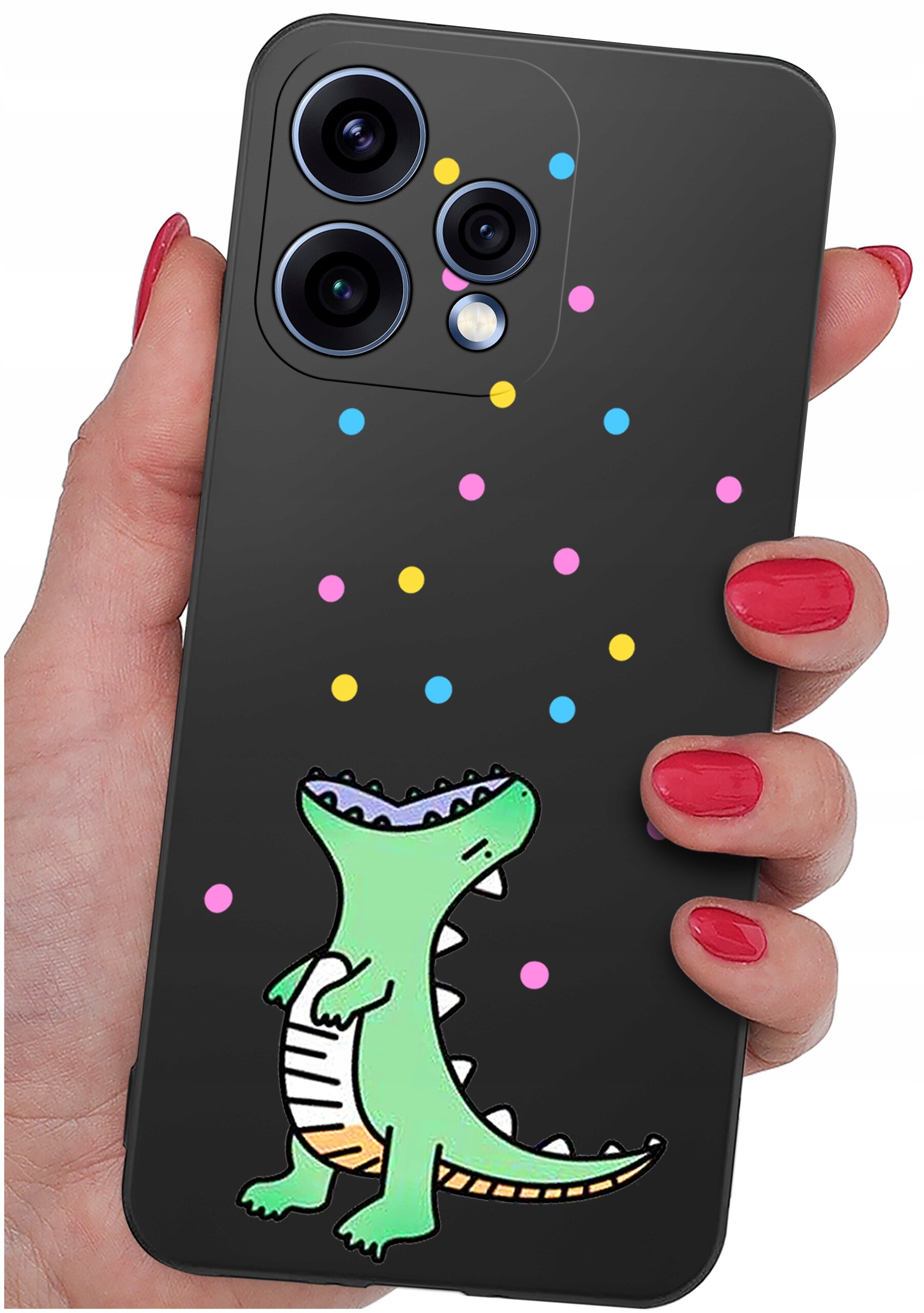Czarna obudowa telefonu z kolorowymi kropkami i rysunkiem zielonego dinozaura. Obudowa jest trzymana w dłoni z pomalowanymi na czerwono paznokciami.