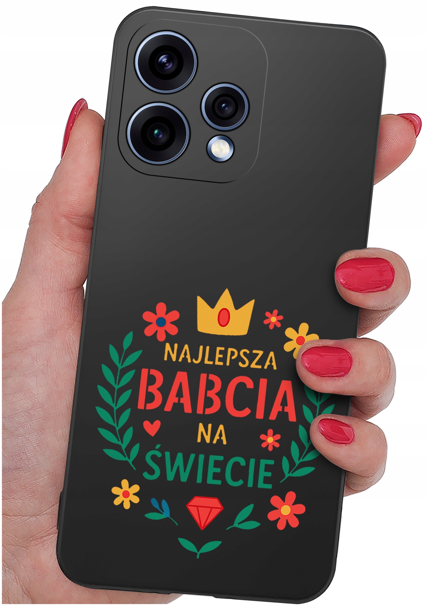 Osoba trzyma telefon w etui z napisem \'NAJLEPSZA BABCIA NA ŚWIECIE\' oraz kolorowymi grafikami kwiatów i korony. Etui jest ciemne, a napis i grafiki są w jasnych kolorach.