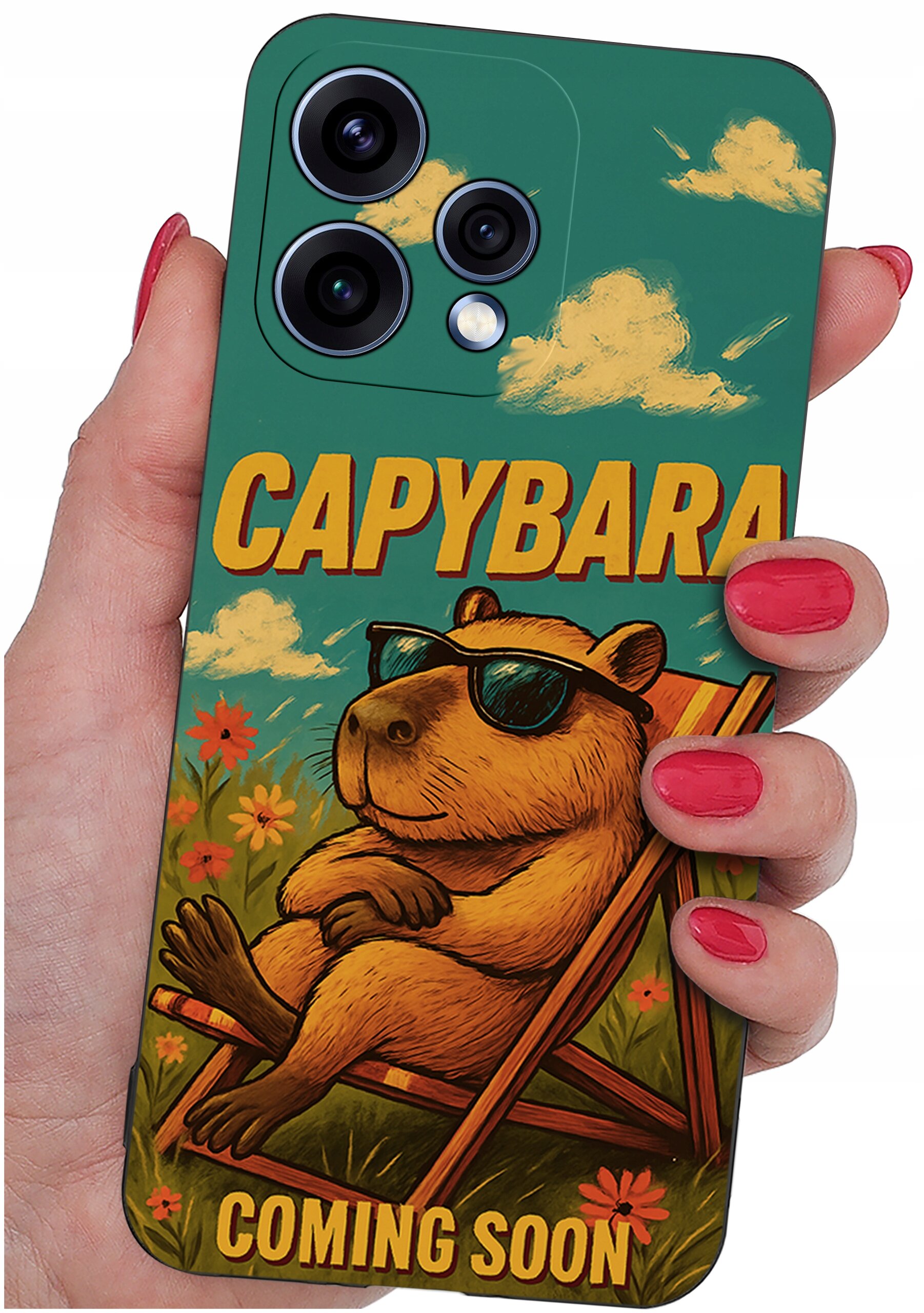 Etui na telefon z grafiką kapibary w okularach przeciwsłonecznych, siedzącej na leżaku w otoczeniu kwiatów. Na etui widnieje tekst: \'CAPYBARA COMING SOON\'.